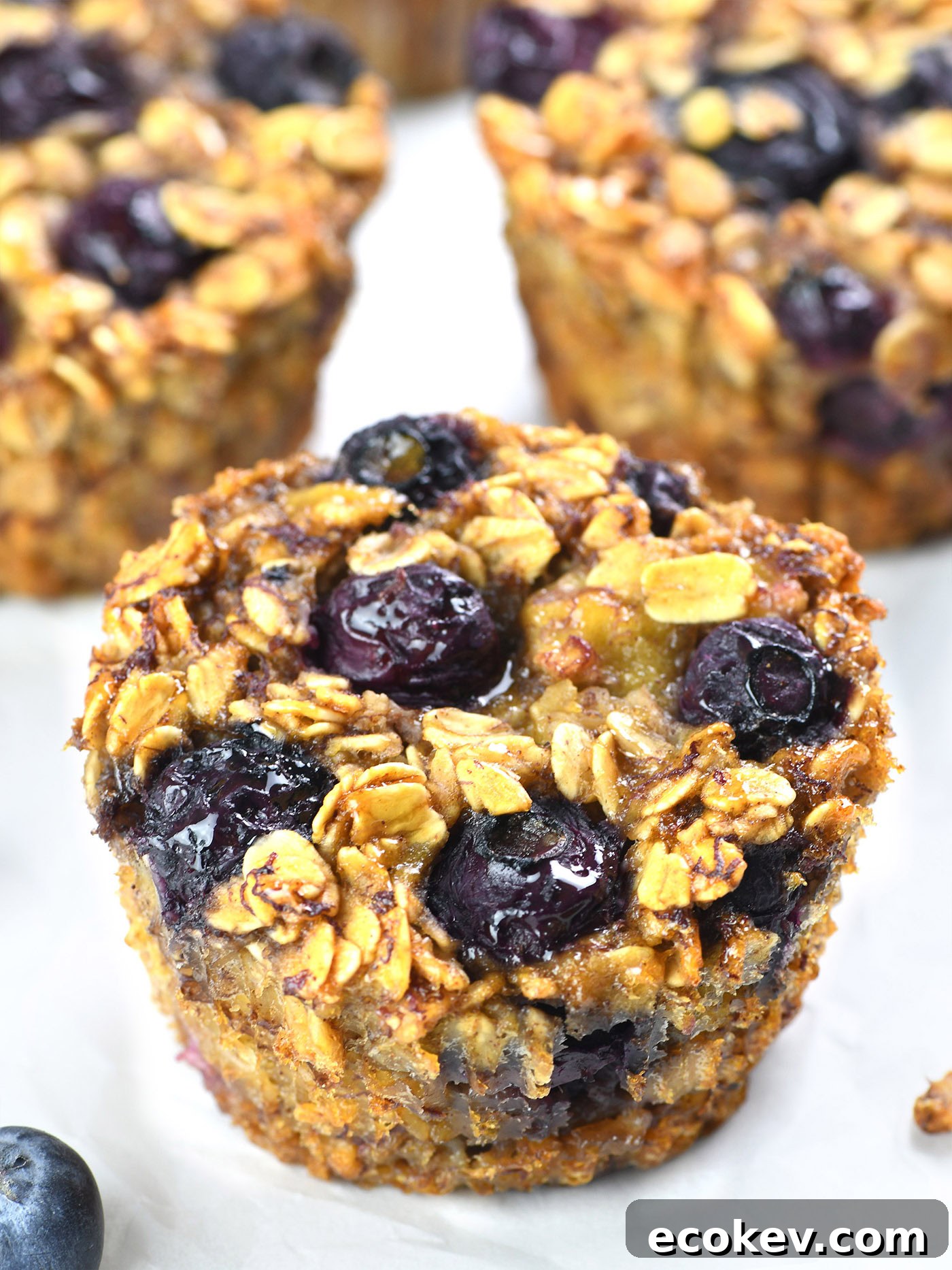 Close-up of a Blueberry Banana Baked Oatmeal Cup topped with fresh blueberries and a golden oat crust.