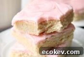 A white plate with a stack of three sugar cookie bars with a bite out of the top bar.