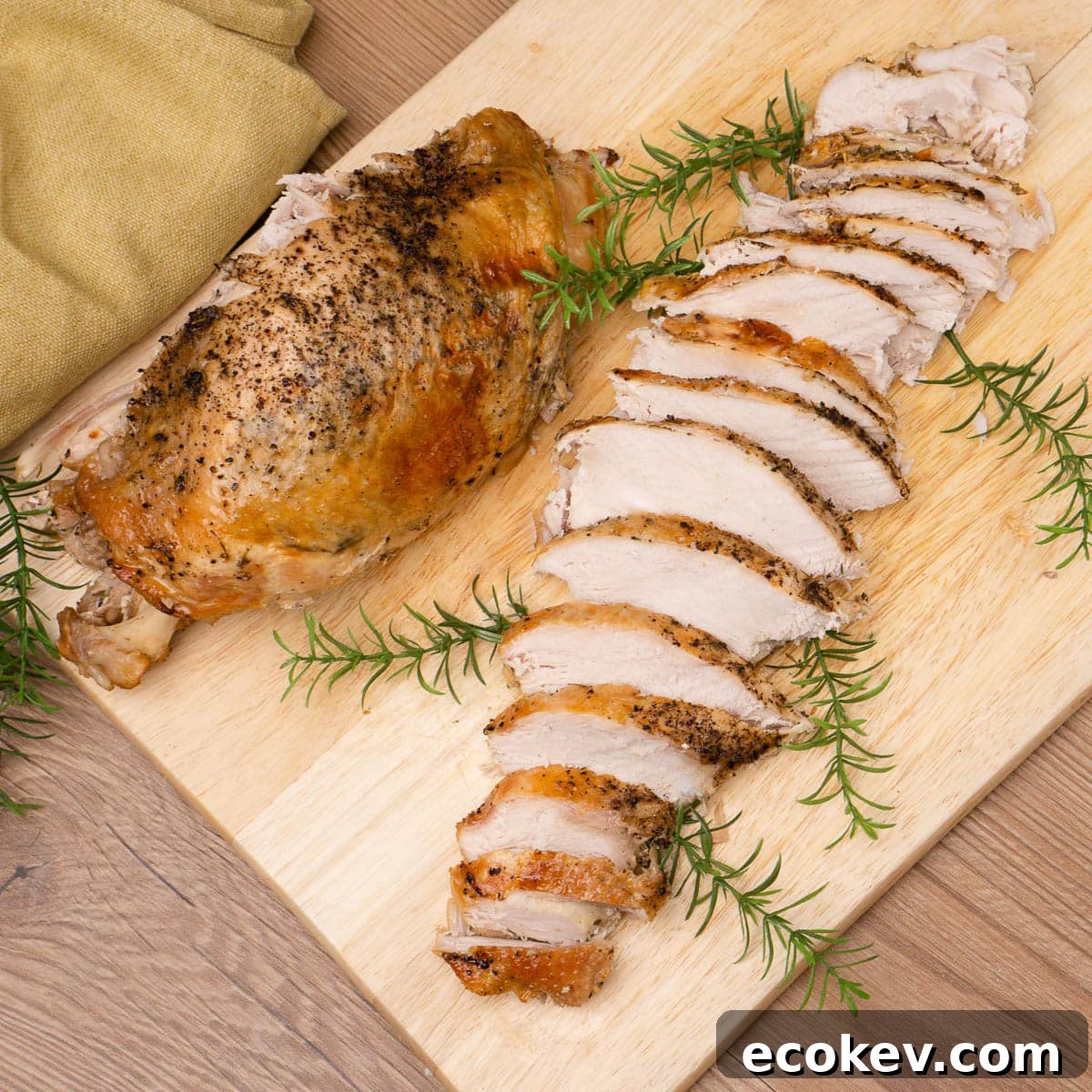 Slow cooker turkey crown breast slices on a wooden copping board with half a turkey crown on the side