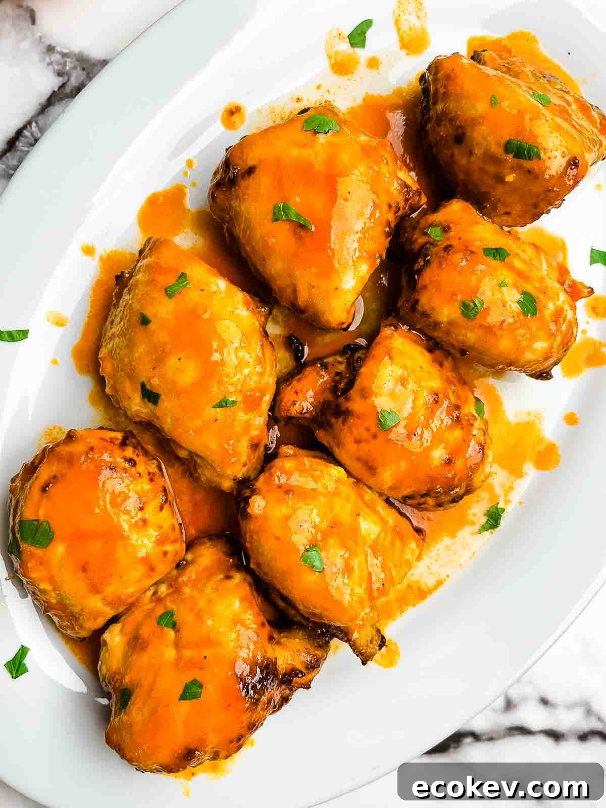 Air fryer boneless buffalo chicken thighs on a white serving platter, garnished with fresh parsley.