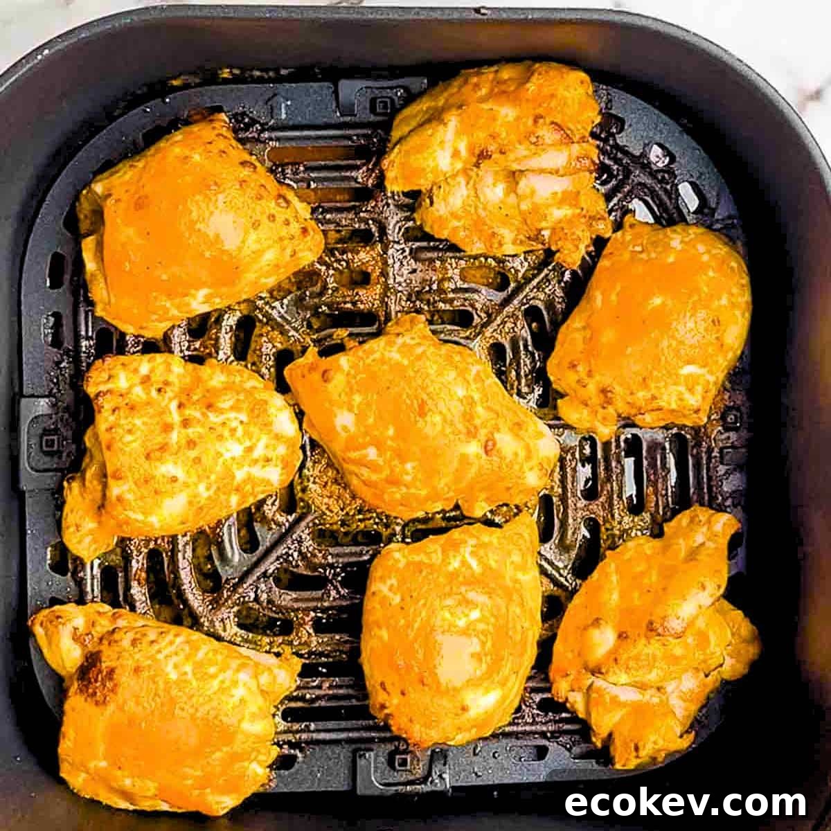 The chicken thighs at the end of the cooking time in the air fryer basket.