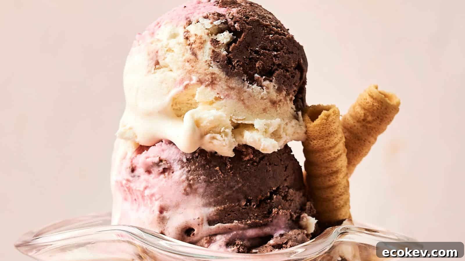 Two scoops of Neapolitan ice cream in a glass dish, featuring chocolate, vanilla, and strawberry flavors, served with two rolled wafer cookies.