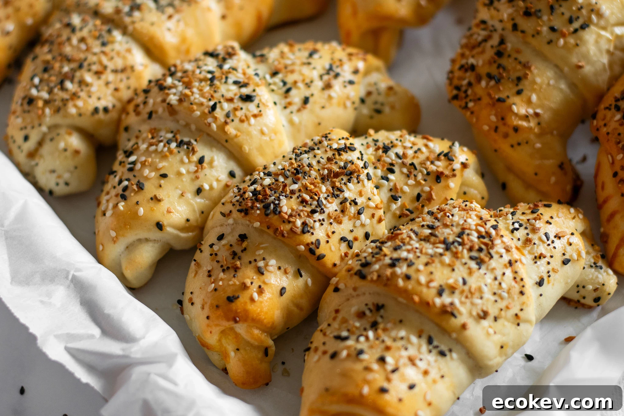 A row of ham and cheese crescent rolls with everything bagel seasoning on the top.