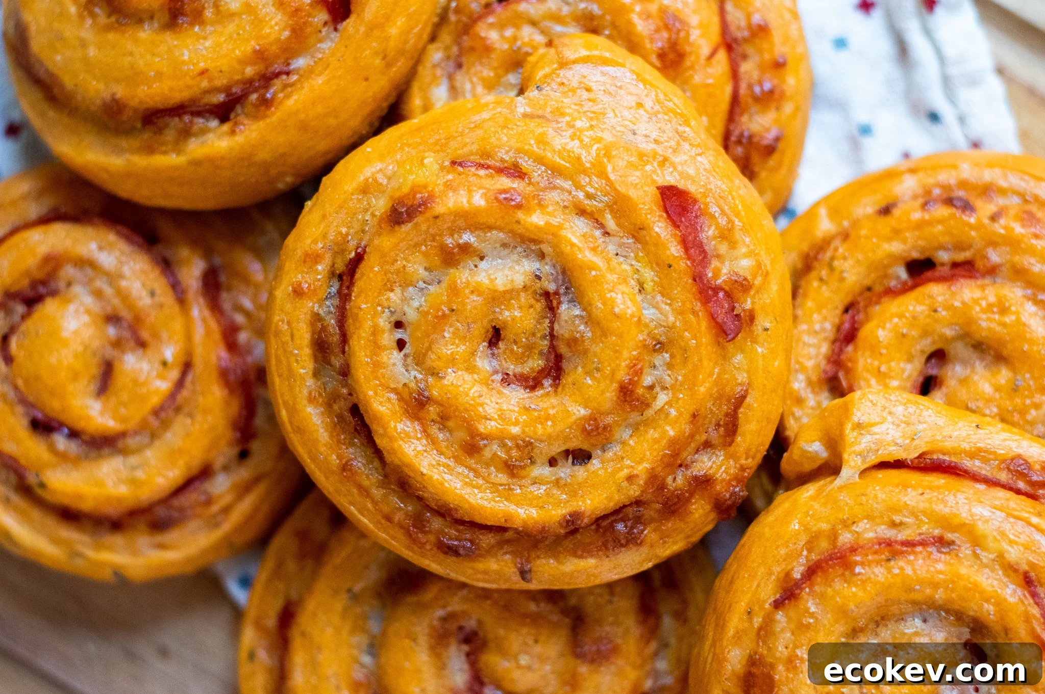 Pizza rolls with pepperoni and cheese on a cutting board.