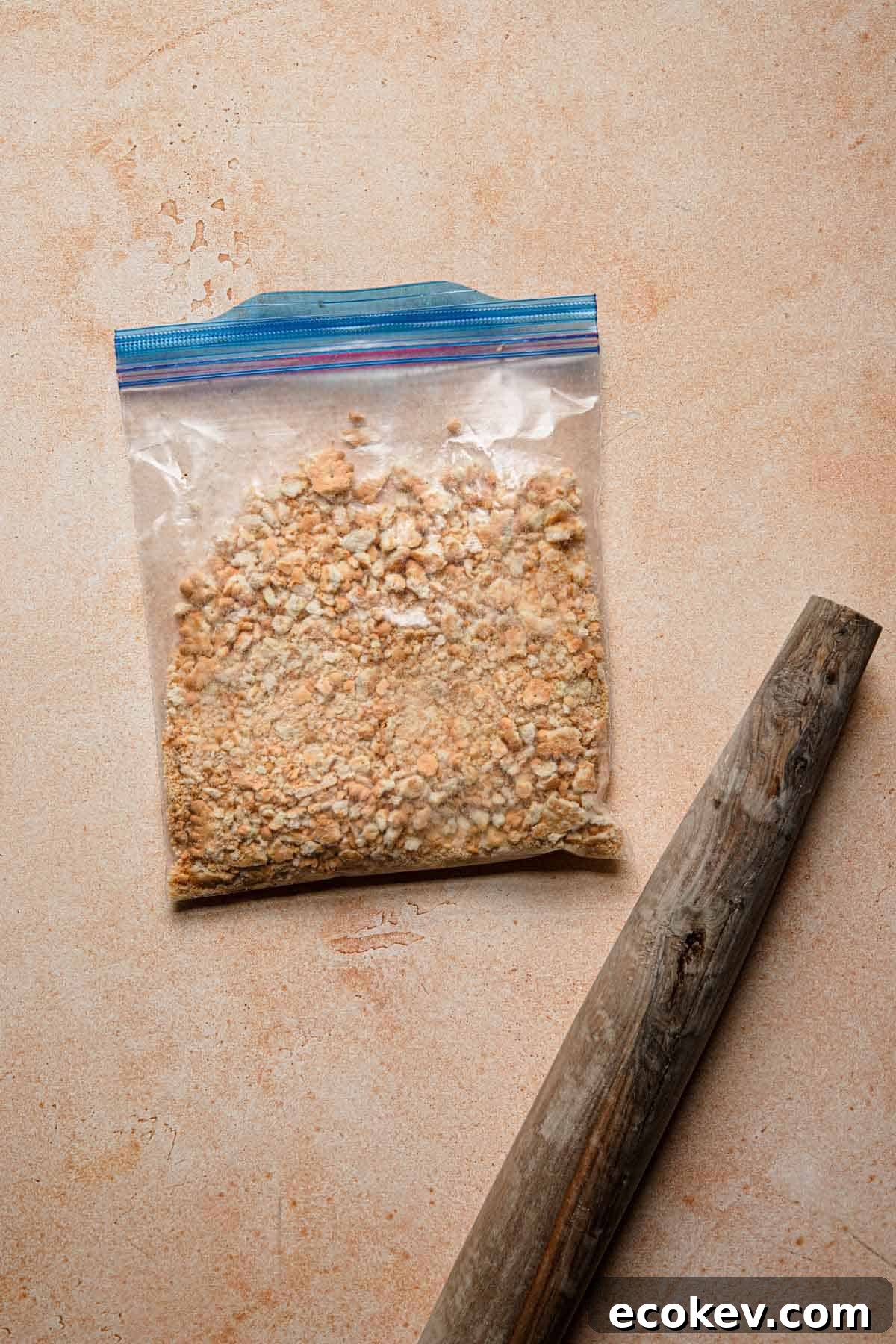Crushed cookies in a bag and a rolling pin next to it.