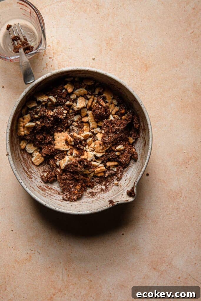 A bowl with cookie dough and crush cookies over it. A measuring cup with a fork next to the bowl.