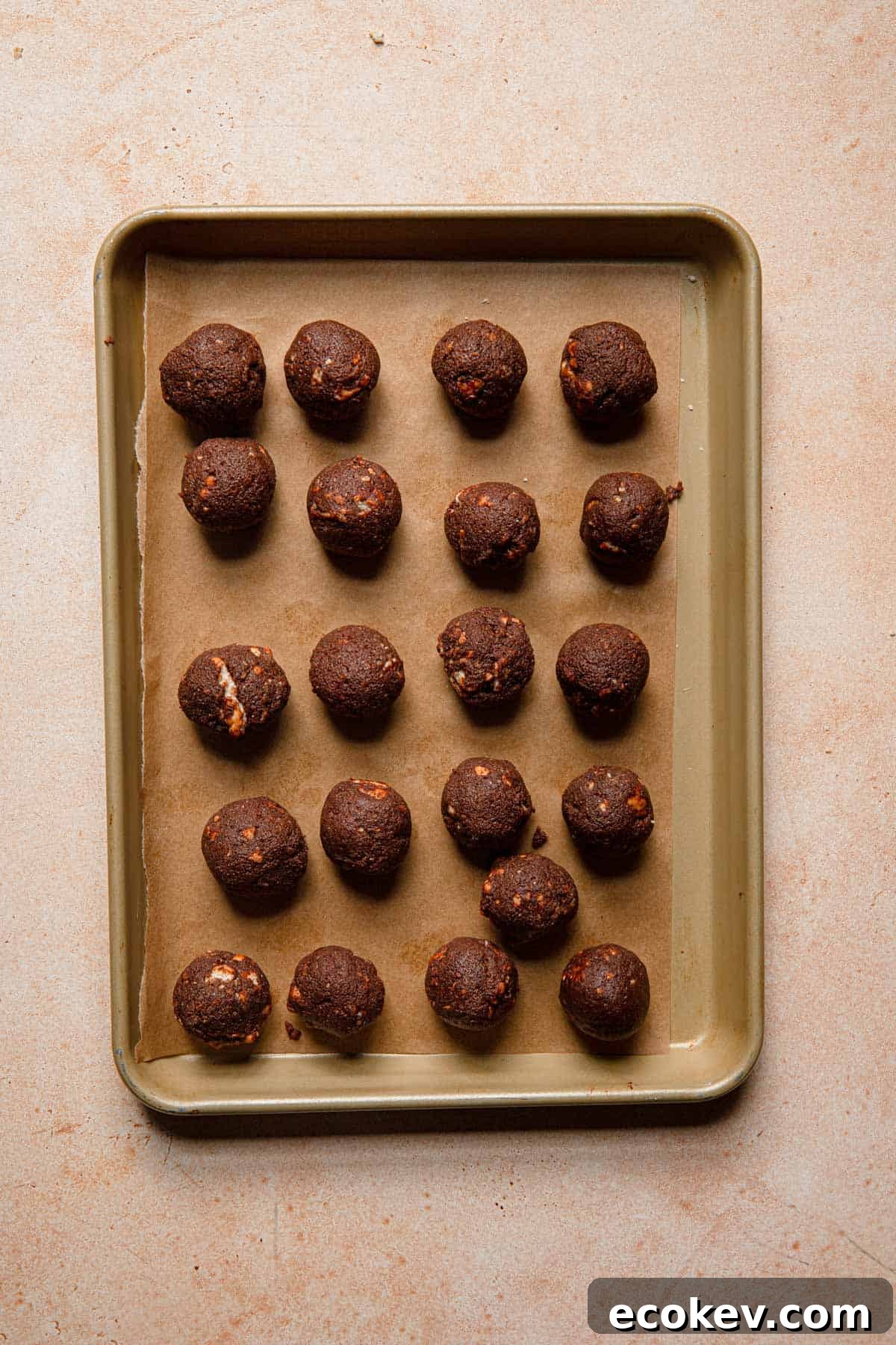 Chocolate cookie balls over a tray lined with parchment paper.