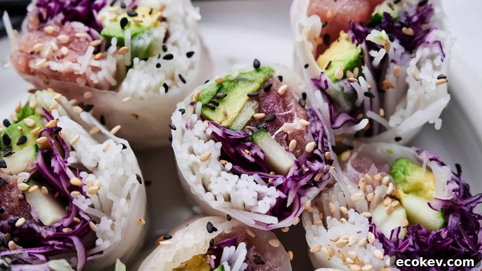 Close-up of sliced spring rolls filled with rice, avocado, purple cabbage, and sesame seeds, arranged on a white plate.