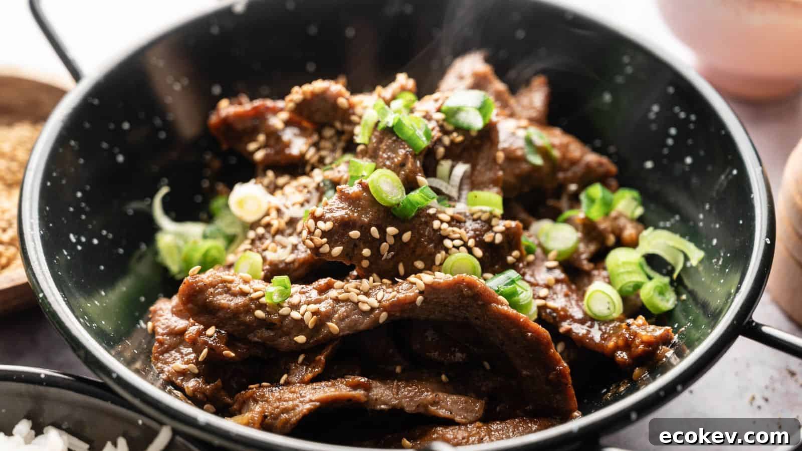 A bowl of cooked beef slices topped with sesame seeds and chopped green onions.