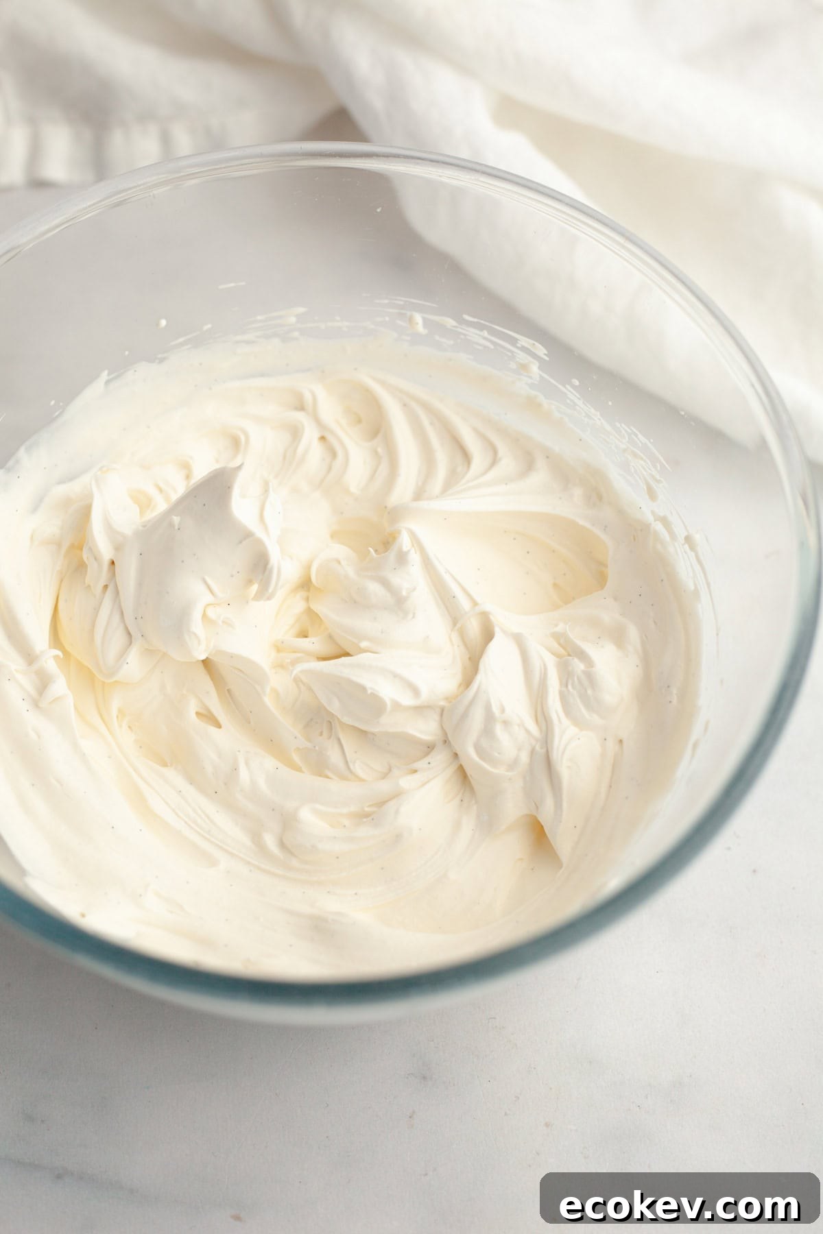 A glass bowl with vanilla bean whipped cream.