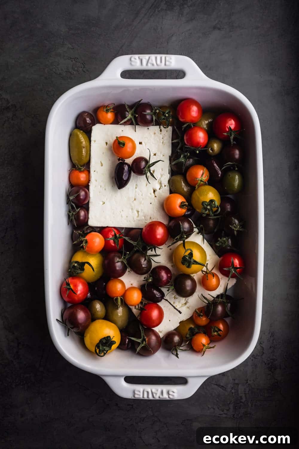 Feta in a baking dish with cherry tomatoes.