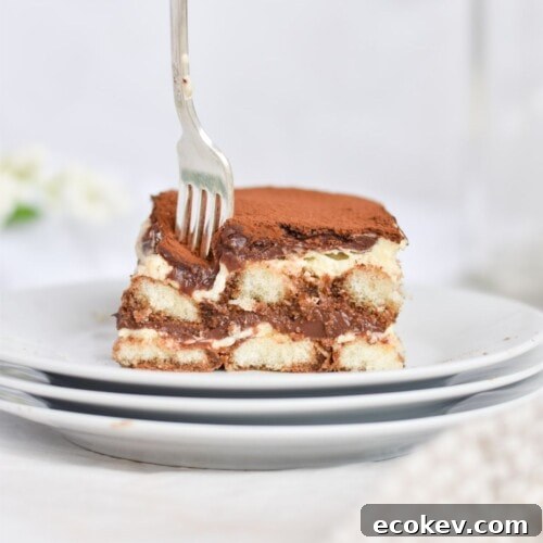 fork going into a slice of tiramisu on white plate.