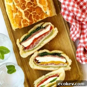 A stuff picnic loaf sliced and ready to eat on a chopping board.