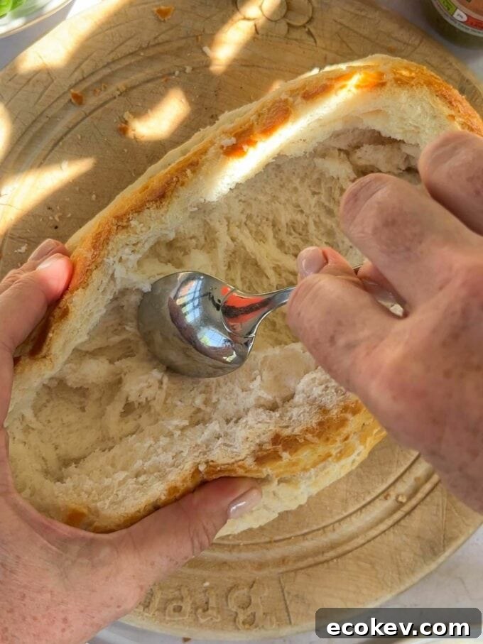 Step 1 in the method of how to make a stuff picnic loaf. Hollow out a loaf of fresh bread and remove the inside.