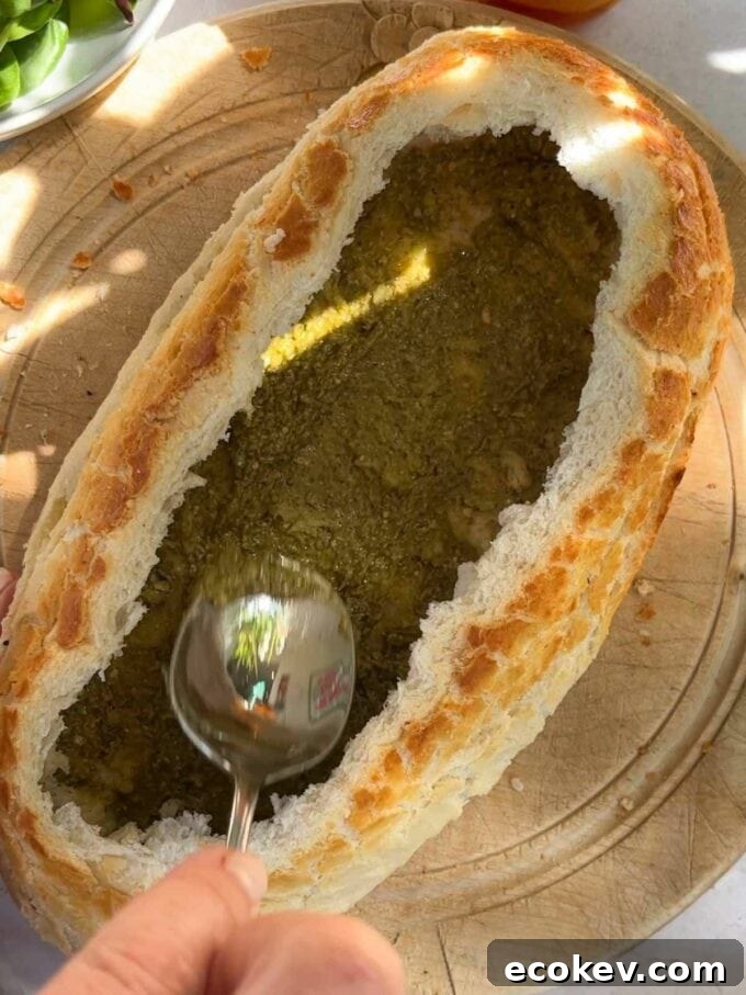 How to make a picnic loaf, step 2. Spread pesto on the bottom of the hollowed out loaf.