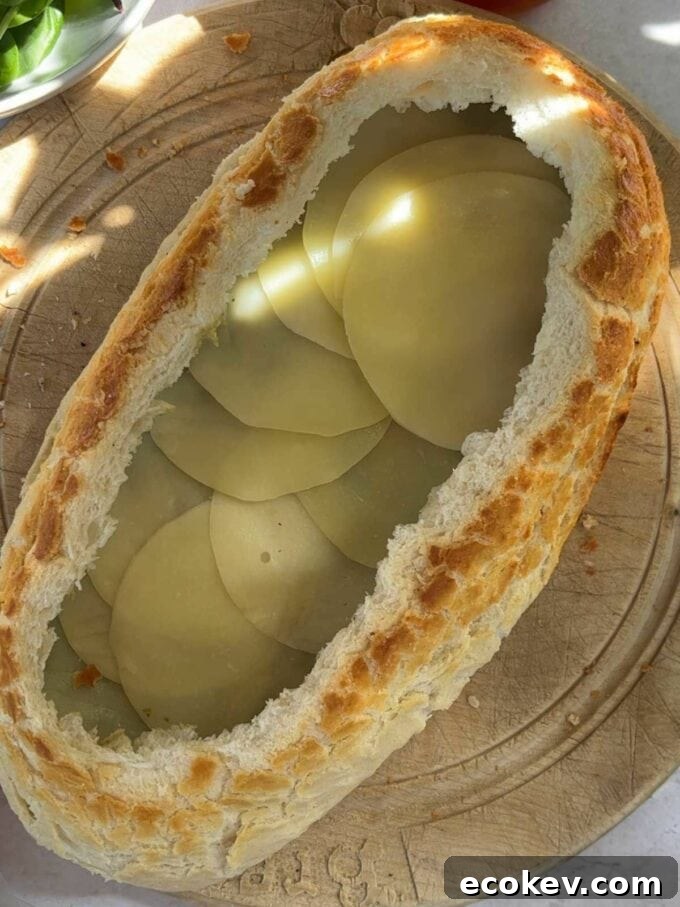 The next step to make a stuff picnic loaf is to add a layer of cheese.