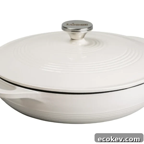 A round white enameled cast iron Dutch oven with a lid and side handles, featuring a metal knob labeled Lodge on top.