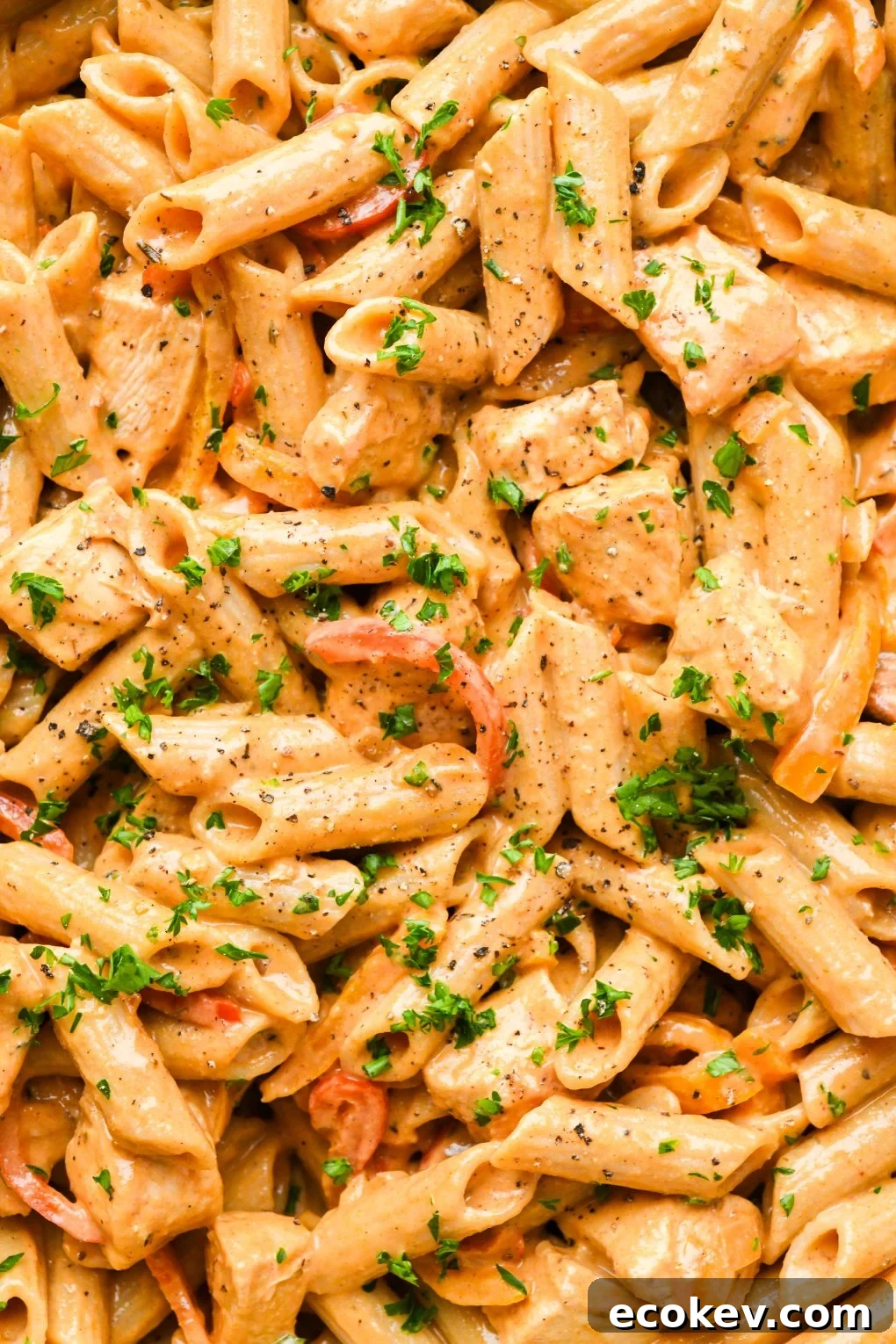 Close up macro style shot of creamy cajun chicken penne pasta topped with chopped parsley. 