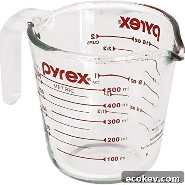 A clear glass Pyrex measuring cup with a handle and spout, marked with red metric and cup measurements up to 500 ml and 2 cups. The Pyrex logo is visible on the side.