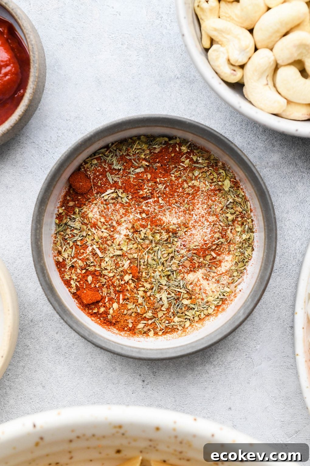 A small shallow bowl filled with homemade Cajun seasoning blend on a light colored background.