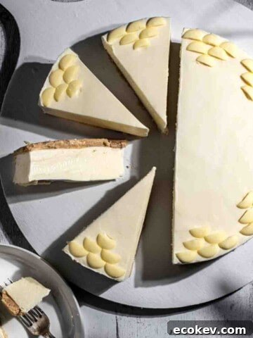 Milkybar cheesecake sliced into slices on a white wooden board.