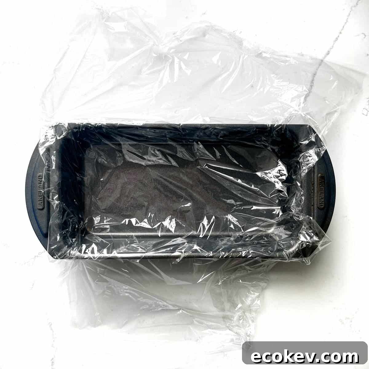 A loaf tin lined with plastic wrap.