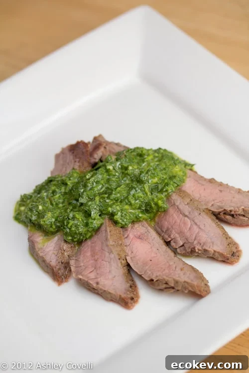 A plate of flank steak topped with chimichurri.