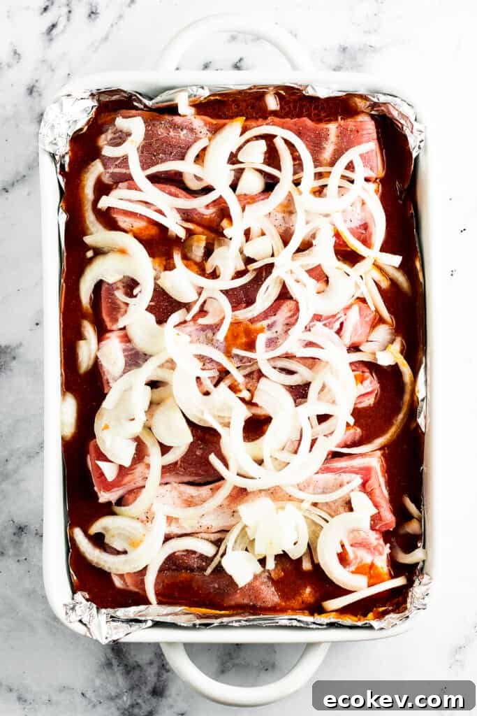 Adding sliced onions on top of the ribs in the baking dish.