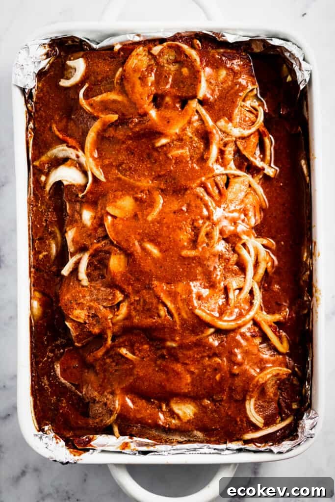 Baked ribs in a sauce with sliced onions on top.