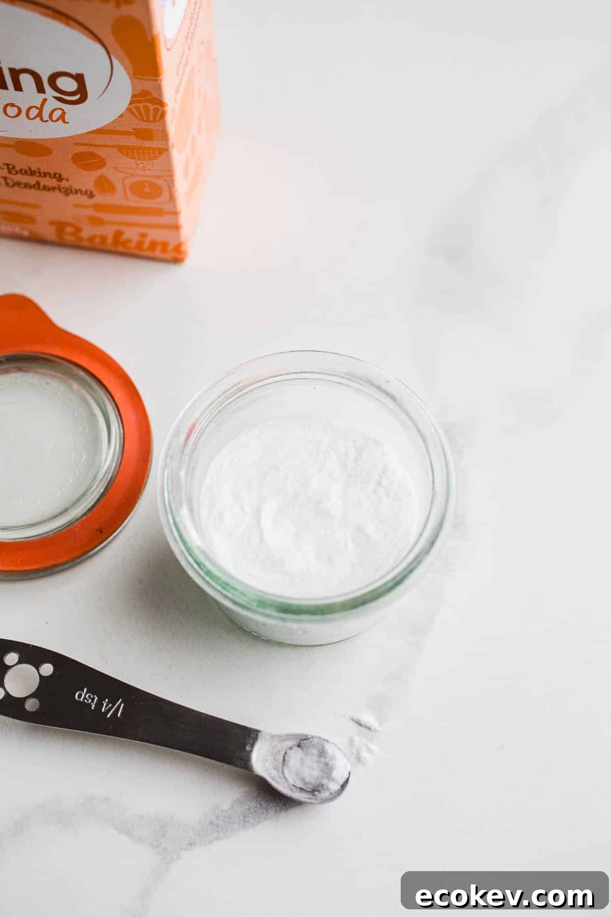 A box and jar of bicarbonate of soda on marble surface.