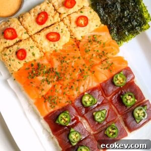 Nigiri-style sushi board with rice on the bottom and three different toppings, spicy crab, salmon and bluefin tuna. On a platter with different sauces on the side.