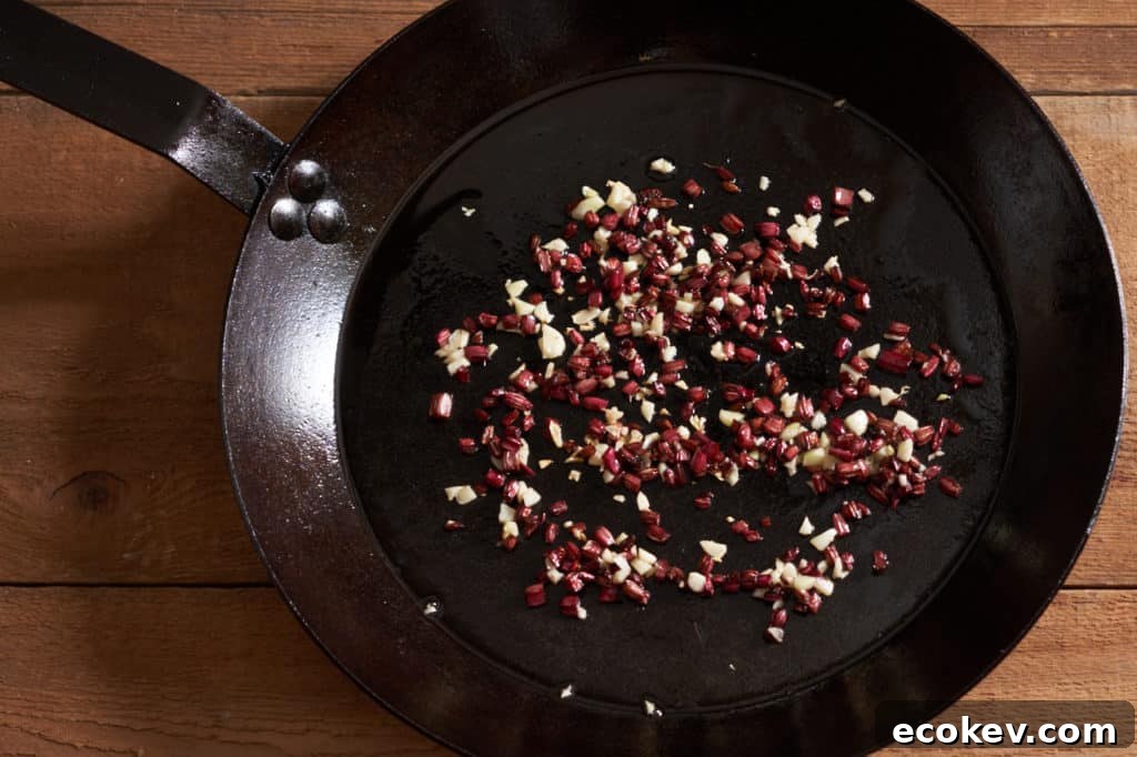 A cast-iron skillet with sauteed beet stems and chopped garlic.