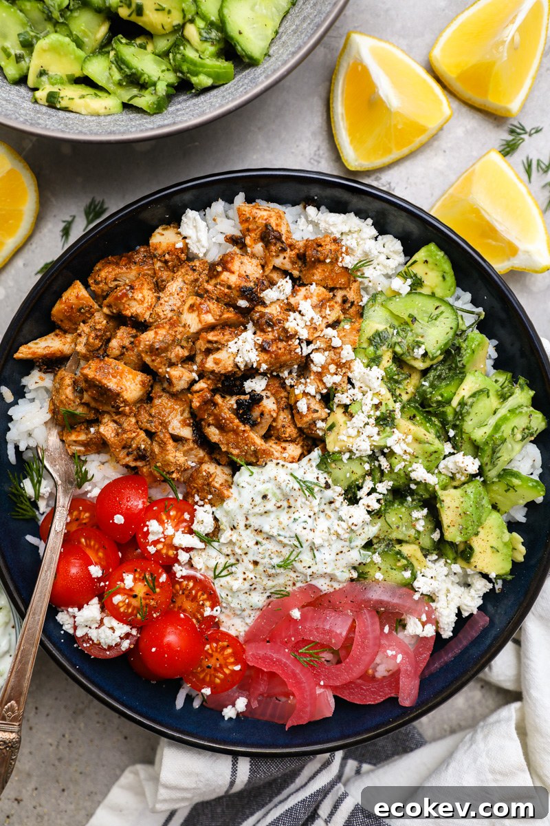 A large blue blue filled with white rice, pickled onion, tomato, marinated chicken, homemade tzatziki and cucumber-avocado salad