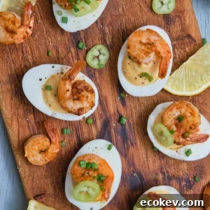 Deviled eggs with Cajun shrimp on a chopping board.