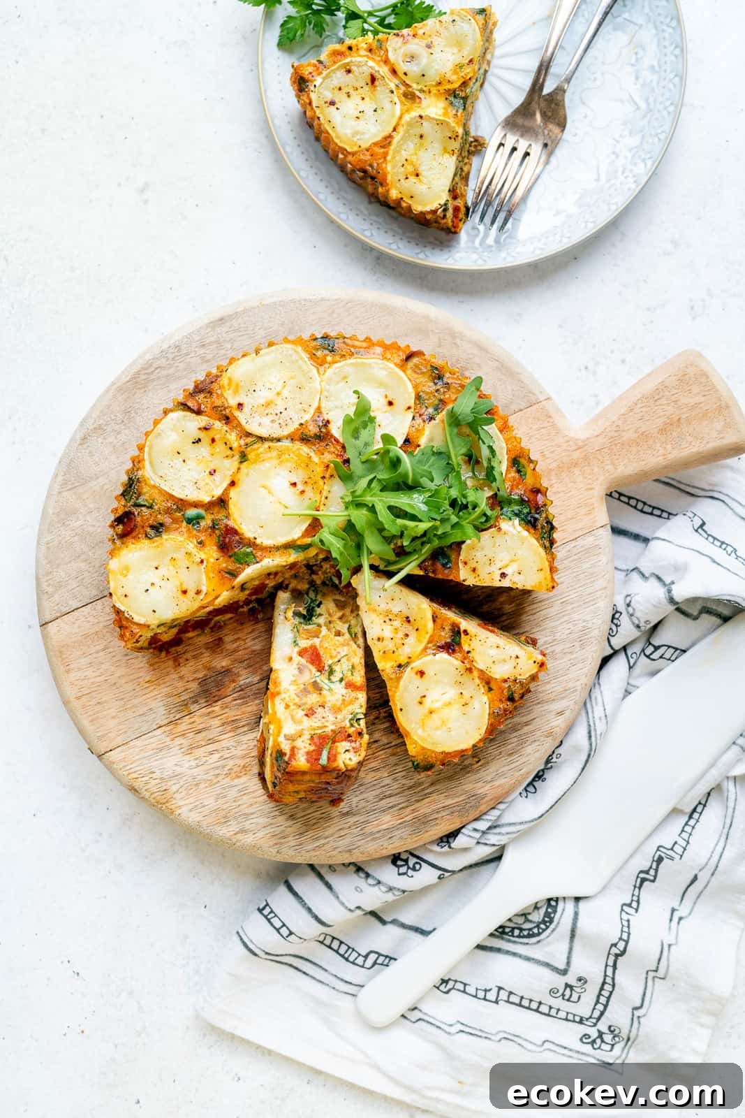 Keto Crustless Quiche topped with goat's cheese on a wooden board, sliced
