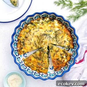 A crustless quiche with spinach and feta sits in a decorative blue pie dish