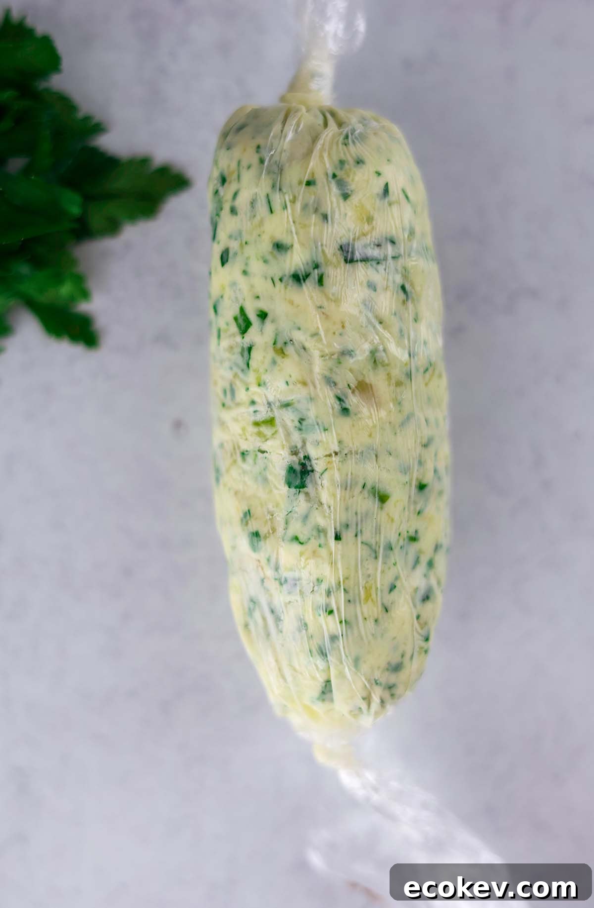 garlic herb compound butter formed into a log in plastic wrap.