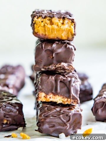 A stack of four chocolate peanut butter cereal bars and the top one has a bite out of it.