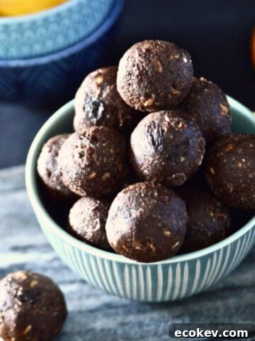 A bowl of chocolate orange energy bites with orange wedges around it.