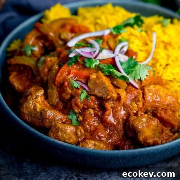 Close up image of chicken Jalfrezi with pilau rice in a blue bowl