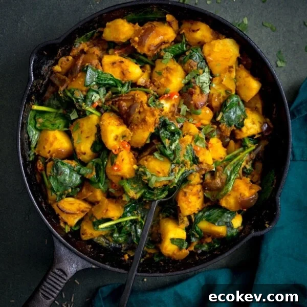 saag aloo in a black pan on a dark background