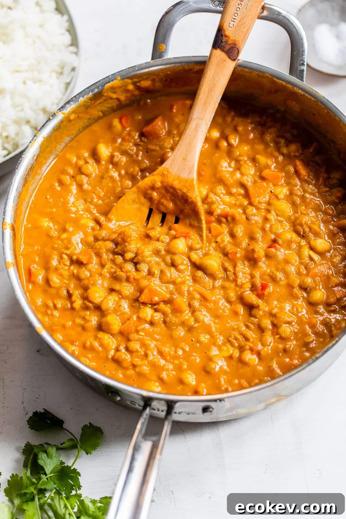 chickpeas, lentils and vegetables cooked in a skillet with an orange sauce