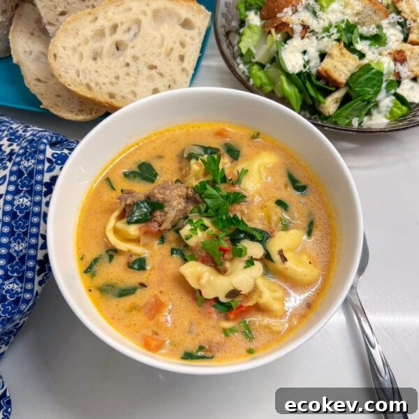 tortellin soup in bowl with caesar salad and fresh bread