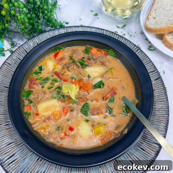 tortellini soup in bowl next to glass and plate of bread