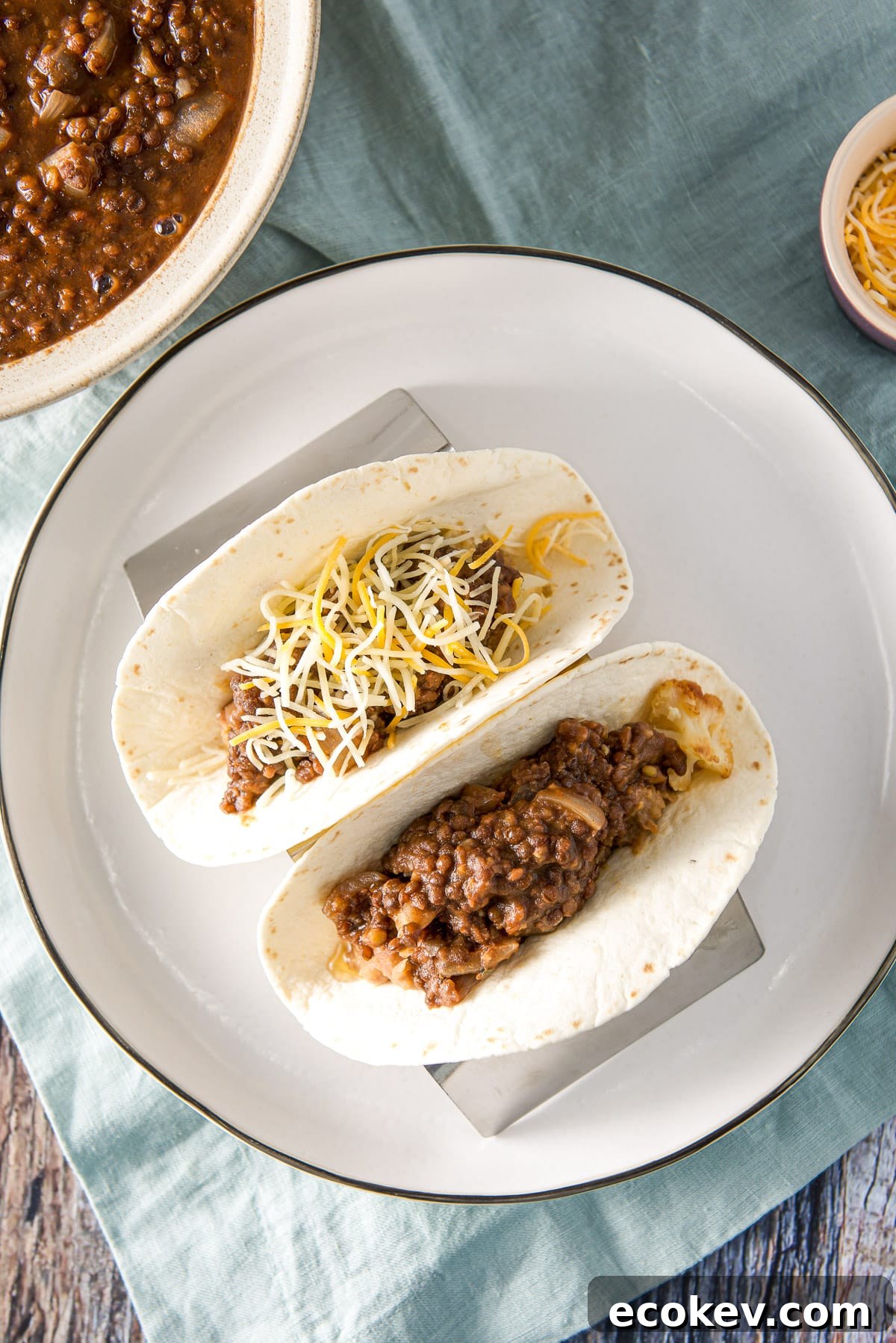 Overhead view of a plate with two tacos on it with lentils off the the side