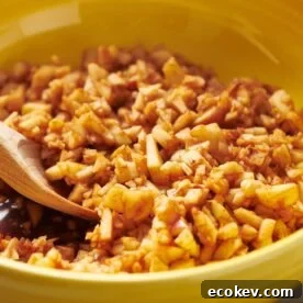 Homemade charoset in yellow bowl with wood spoon.