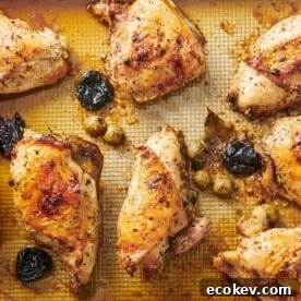 Chicken Marbella on a lined baking sheet.