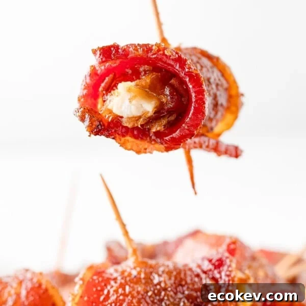 Bacon wrapped date being held over others.