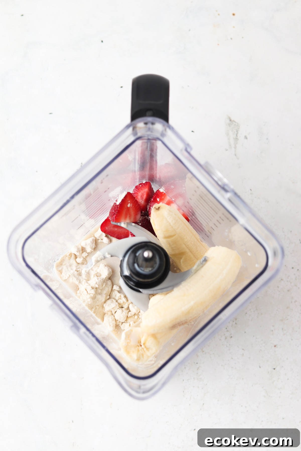 Strawberries, bananas, protein powder and milk in a blender. 