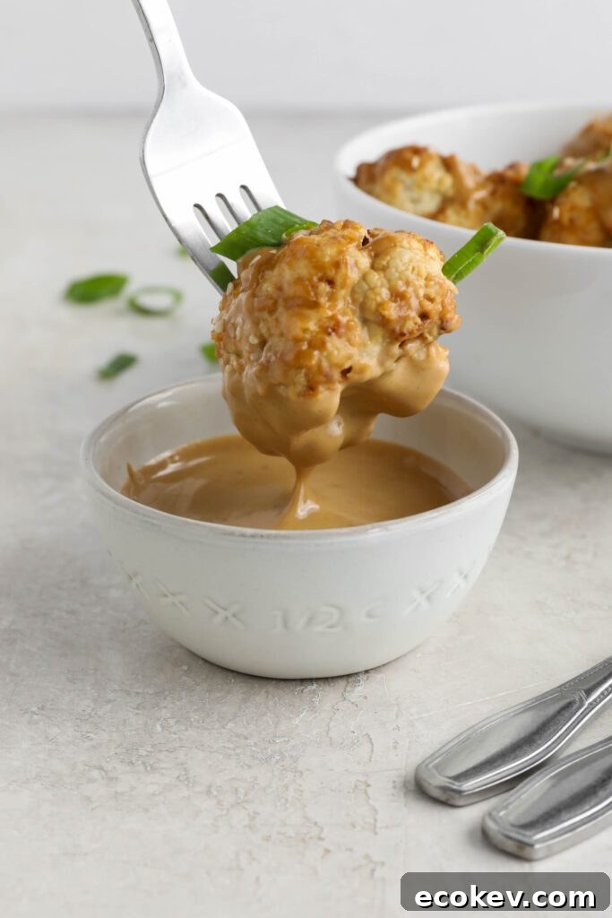 fork dipping air-fried cauliflower in Spicy SunButter sauce bowl by Flora & Vino